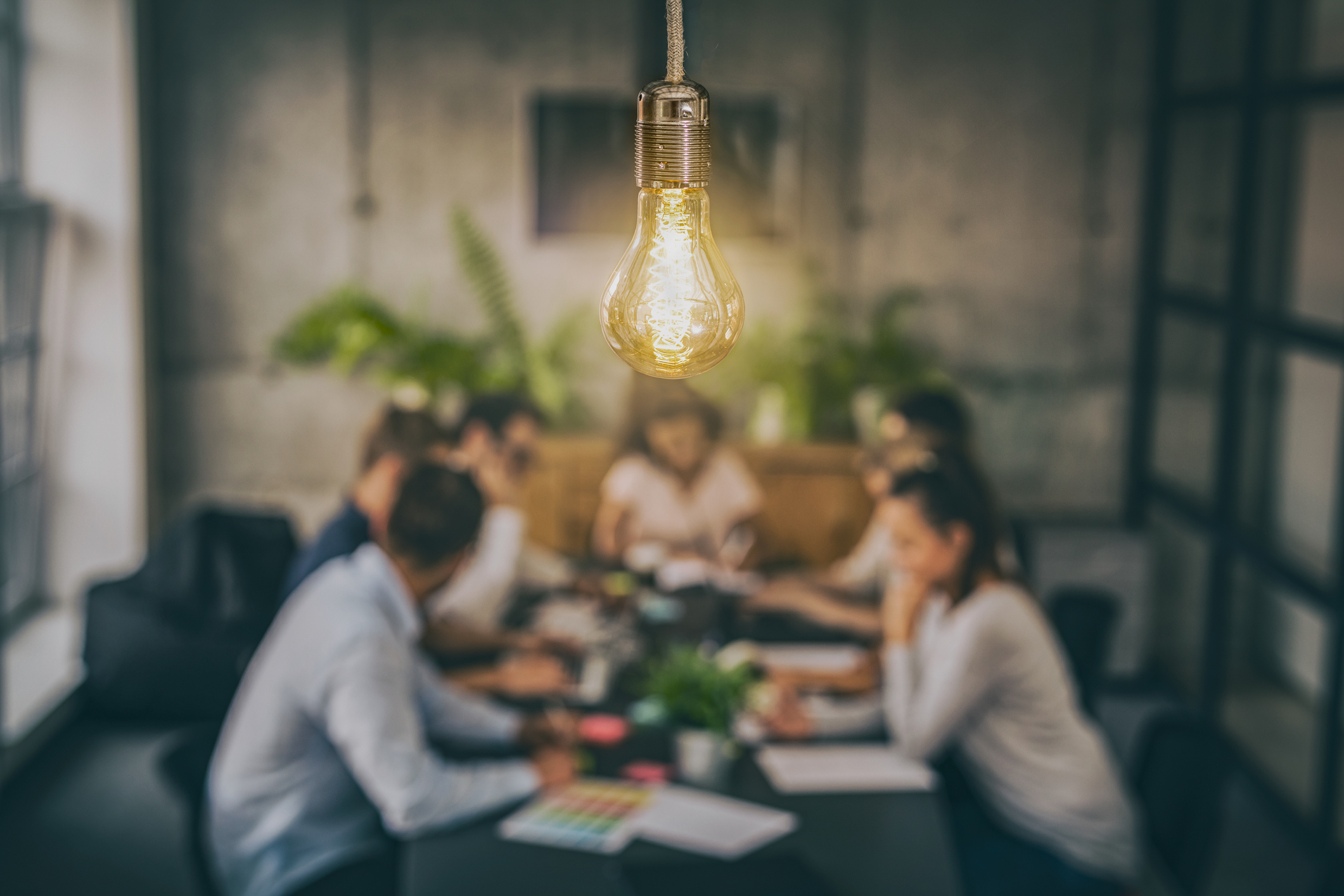 Photo of light bulb above a team in discussion