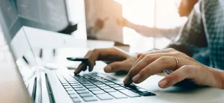 Photo of person's hands typing on laptop keyboard