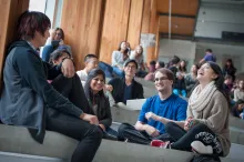 Students sitting on steps inside a UBC building discussing and laughing