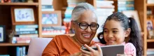 Photo of grandmother with granddaughter using a tablet