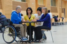 Photo of health mentor in a wheelchair and students talking at a table
