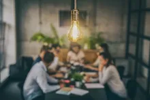 Photo of light bulb above a team in discussion
