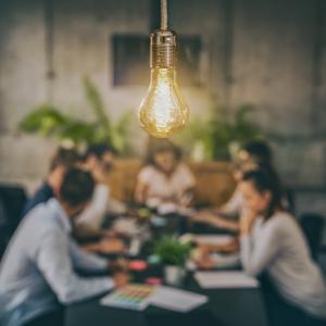 Photo of light bulb above a team in discussion